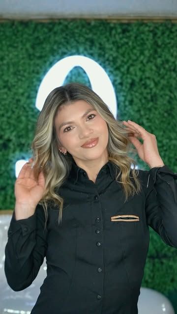 Mujer sonriente de negro frente al muro verde con la O iluminada