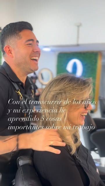 Osvaldo Muñoz riendo junto a una clienta en la silla del salón